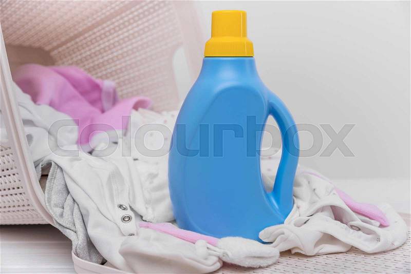 Bottle of laundry detergent in a basket of dirty baby clothes. Close-up, stock photo