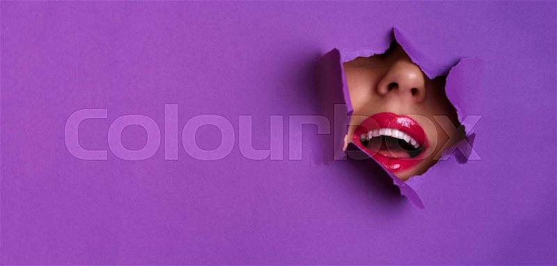 View of bright lips through hole in violet paper background. Make up artist, beauty concept. Cosmetics sale. Beauty salon advertising banner with copy space, stock photo