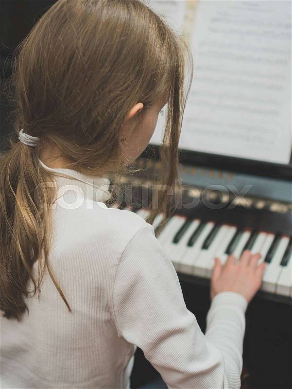 Little girl learning to play the piano, stock photo