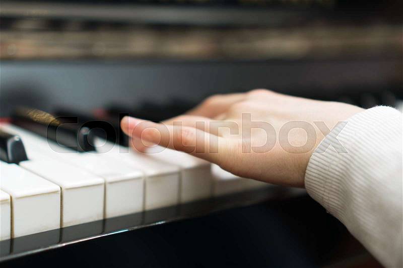 Child learning to play the piano, stock photo