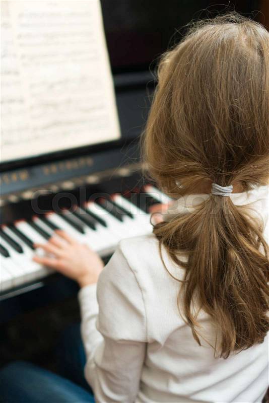 Little girl learning to play the piano, stock photo