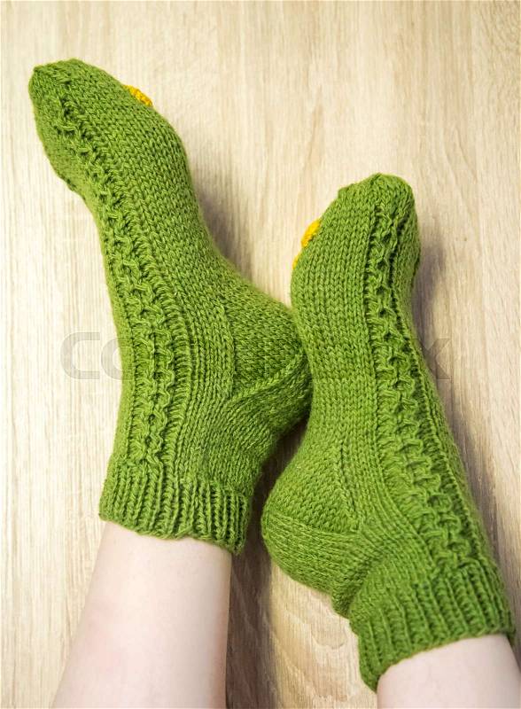 A woman wearing warm hand craft socks. Knitted form a natural sheep wool yarn. Winter clothing. On a wooden background, stock photo