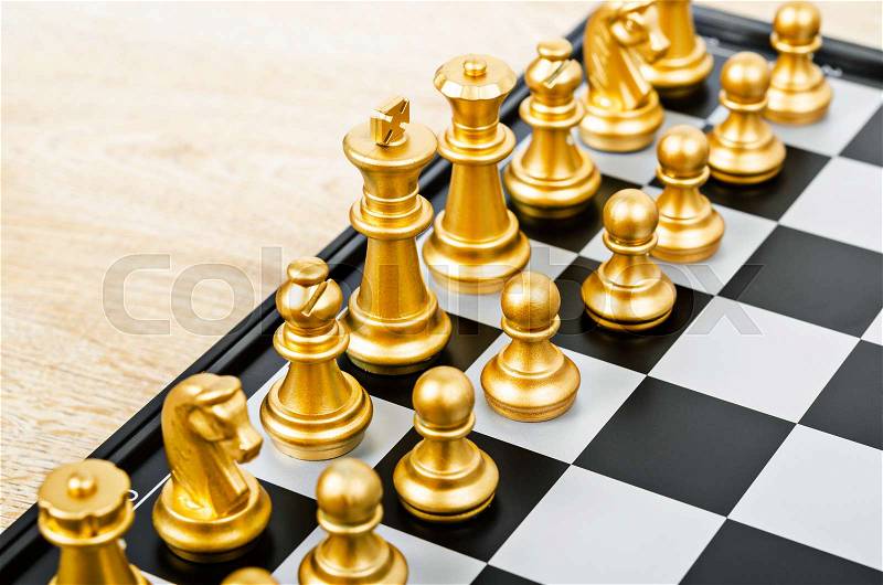 Chess game face with the another gold team on wooden background (Concept for company strategy, business victory or decision), stock photo