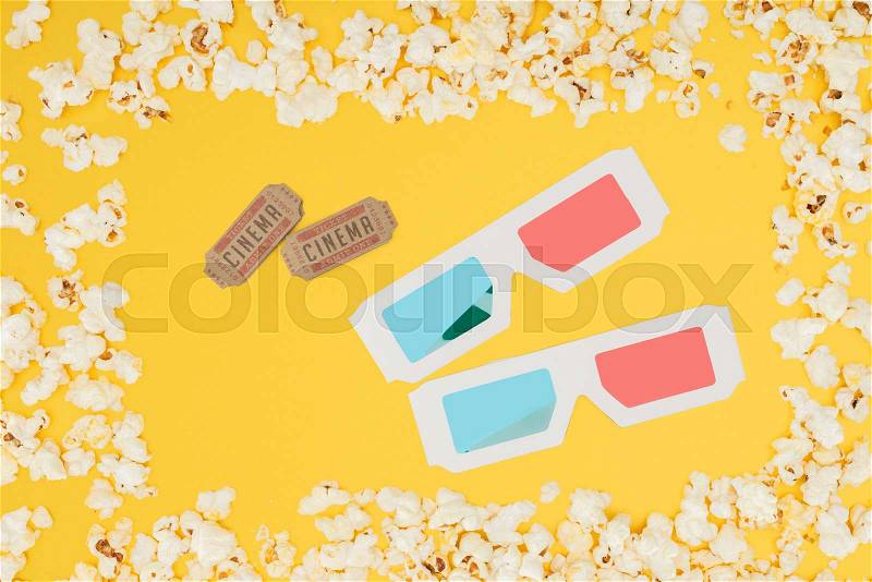Cinema tickets and 3d glasses in frame made of tasty popcorn isolated on yellow, stock photo
