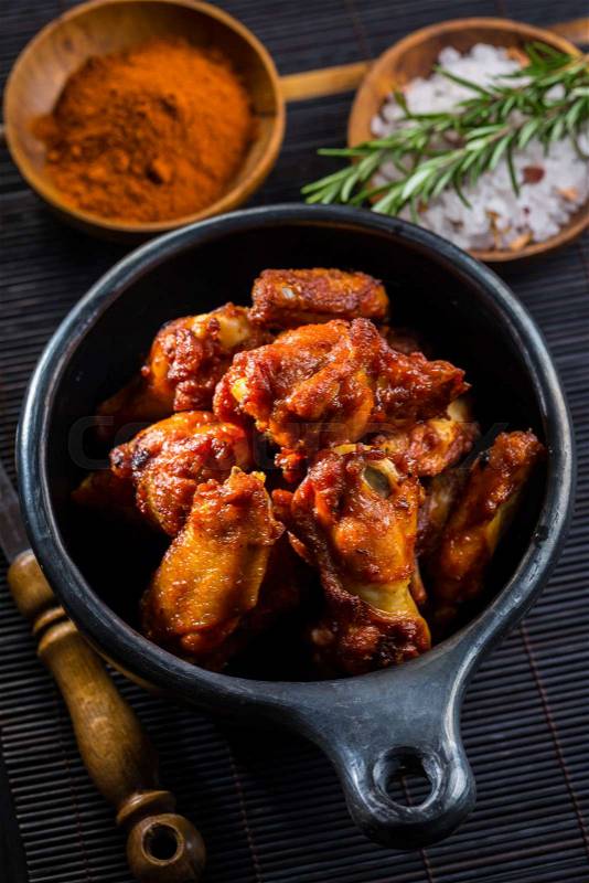 Hot and spicy chicken wings with spices on dark background , stock photo