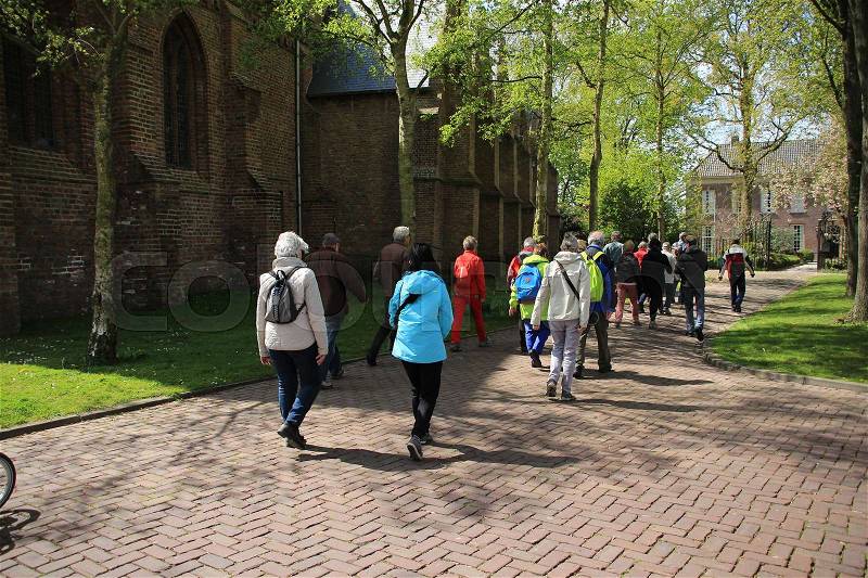 The group with the guide is walking along the church in the village Abbenbroek in the beautiful autumn, stock photo