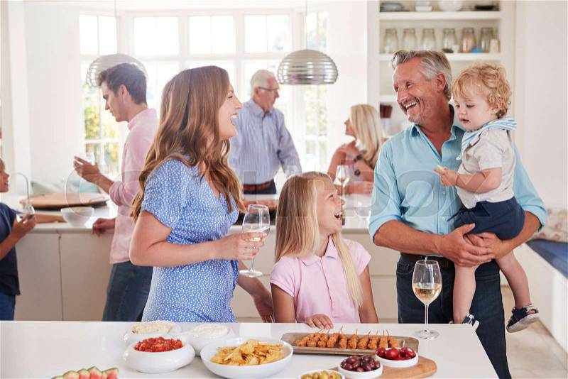 Multi-Generation Family And Friends Gathering In Kitchen For Celebration Party, stock photo