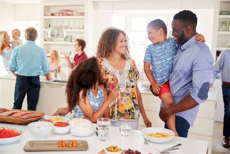 Multi-Generation Family And Friends Gathering In Kitchen For Celebration Party, stock photo