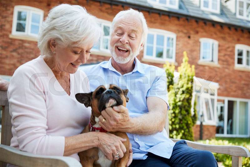 Retired Couple Sitting On Bench With Pet French Bulldog In Assisted Living Facility, stock photo