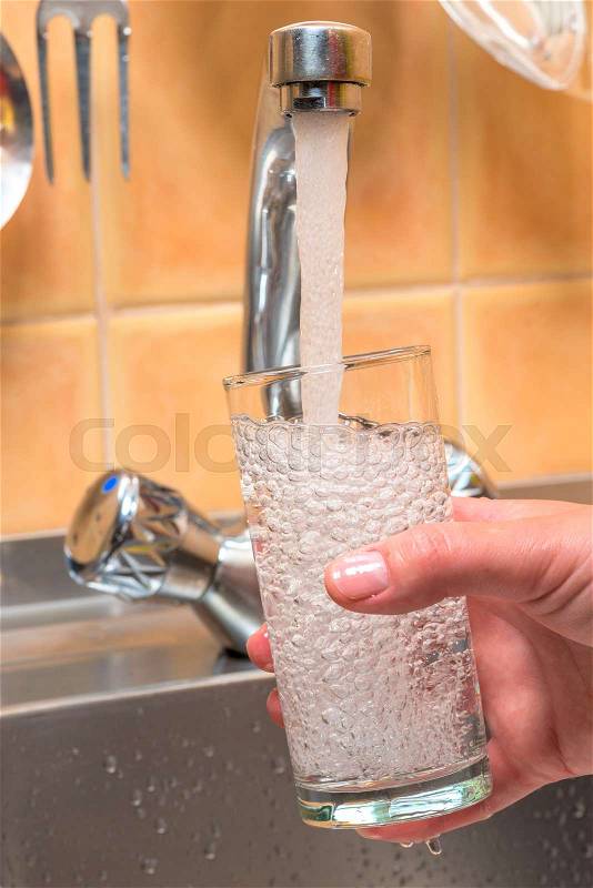 Clean drinking water is poured from the kitchen tap into the glass, stock photo