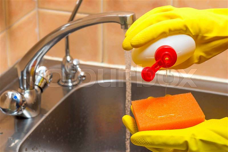 Gloved hands with dishwashing liquid and a sponge in the kitchen closeup, stock photo