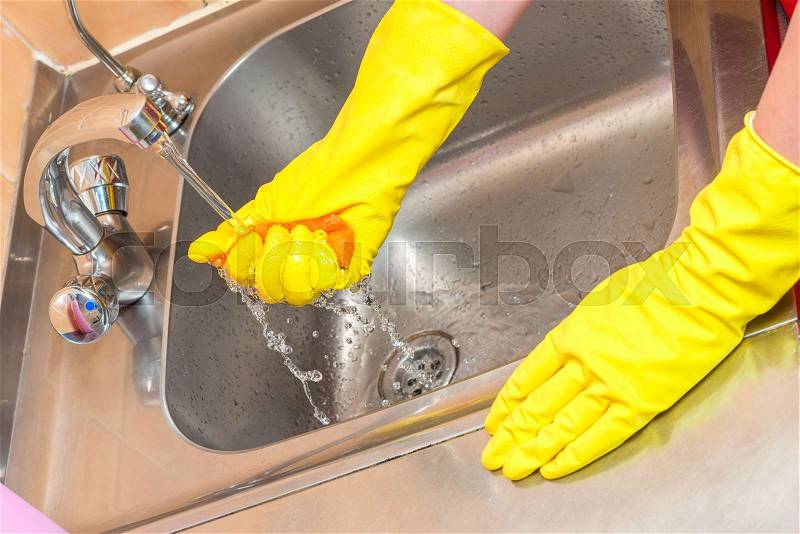 Woman housewife working in the kitchen - hands with a sponge at the sink, stock photo