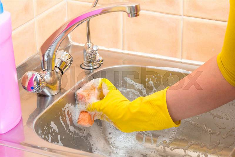 Foam cleaning dirty kitchen sink, hand closeup, stock photo