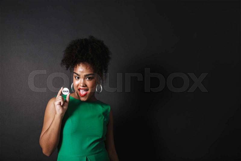 Image of a happy african woman posing isolated over black wall holding chip, stock photo