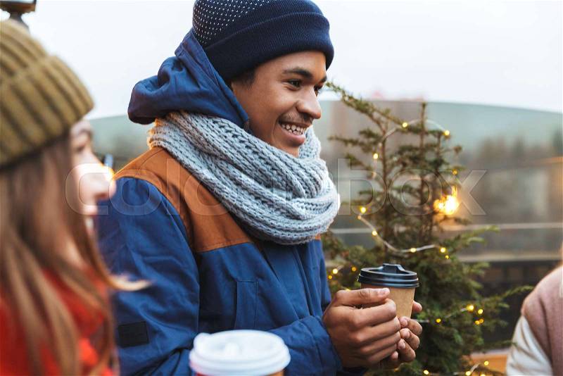 Image of a happy young friends talking with each other drinking coffee outdoors winter concept, stock photo
