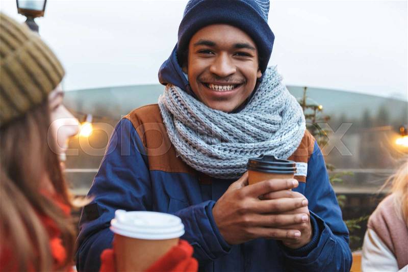 Image of a happy young friends talking with each other drinking coffee outdoors winter concept, stock photo