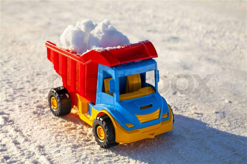 Toy truck removes snow on the road in winter, stock photo