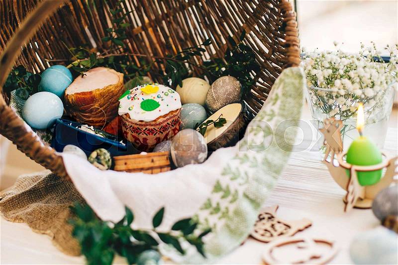 Traditional Easter basket with stylish eggs, easter bread, ham, sausage, butte, and flowers, candle on rustic wooden background. Happy Easter concept. Traditional ..., stock photo
