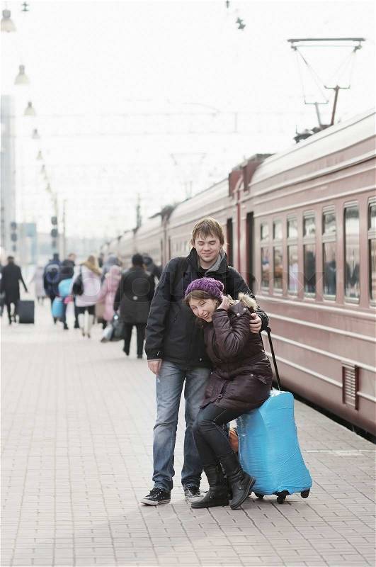 Happy young couple waiting for train on railway station platform, stock photo
