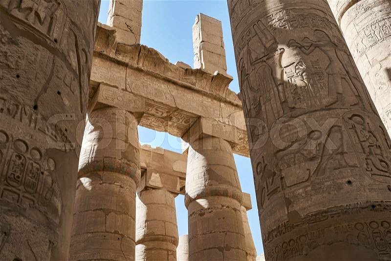 View at the ancient columns with egyptian hieroglyphs on the blue sky background in Karnak Temple in Egypt. Sun shines onto them. Horizontal, stock photo