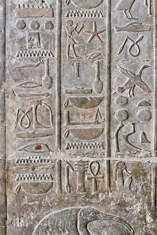 Closeup photo of the ancient egyptian wall with animal and human images and hieroglyphs. Vertical, stock photo