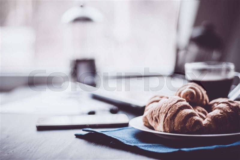 Mate moody color. concept of work. Macro shot of Smartphone and Laptop fresh croissants and coffee black background, stock photo
