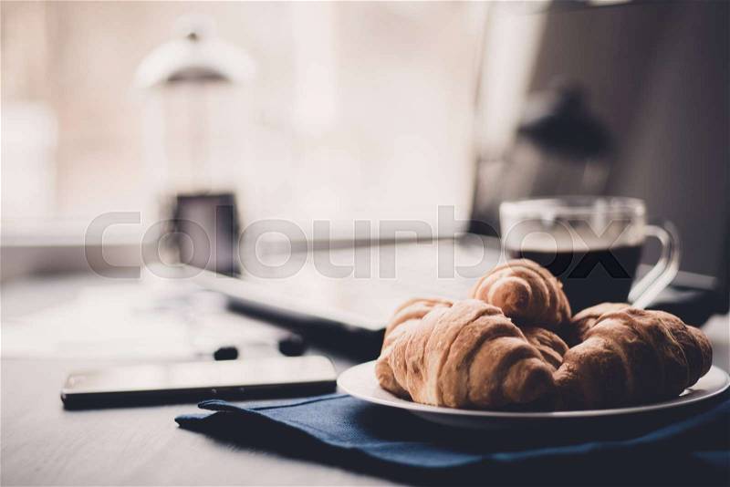 Mate moody color. concept of work. Macro shot of Smartphone and Laptop fresh croissants and coffee black background, stock photo