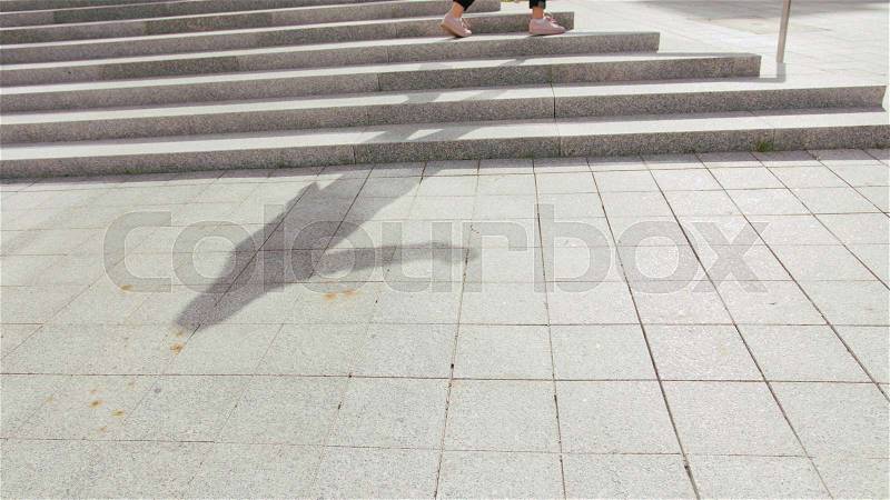 A young woman\'s shadow dancing outside. The y standing on the stairs. Medium shot, stock photo