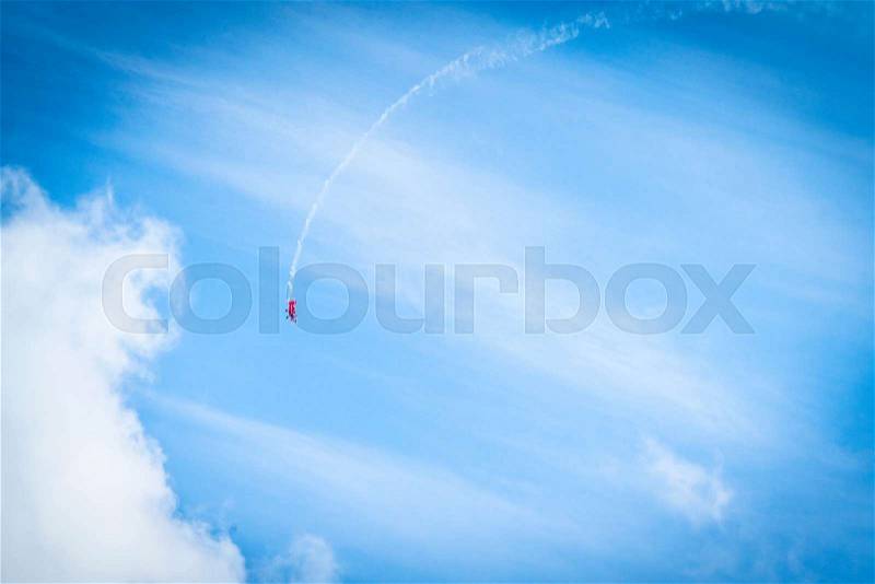 Veteran airplane makes a loop in the sky with smoke at its tail, stock photo