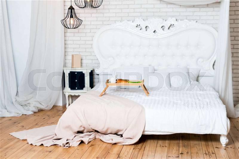 King size bed in loft apartment. Breakfast in bed, a tray of coffee, croissants and flowers. Honeymoon. Early morning at the hotel, stock photo