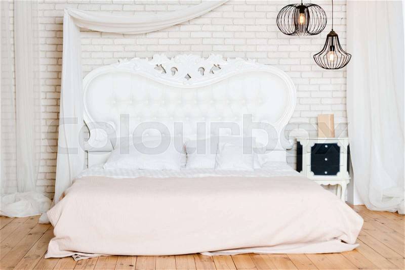 King size bed in loft apartment. Loft style bedroom with white design, stock photo