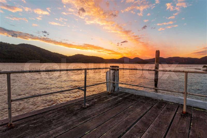 Peat Island timber jetty as the sun sets behind the mountains, stock photo