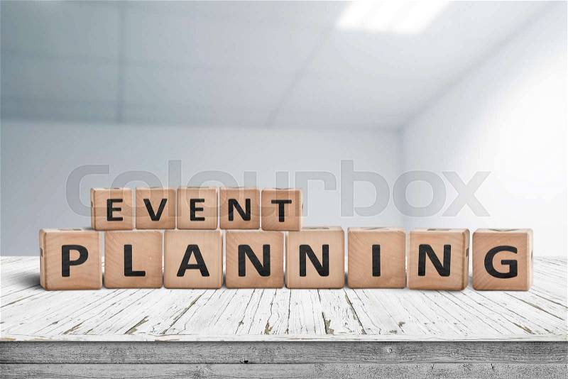 Event planning sign on a wooden desk in an office with a blurry grey background, stock photo