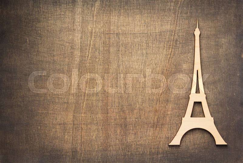 Wooden eiffel tower toy at plywood background surface, stock photo