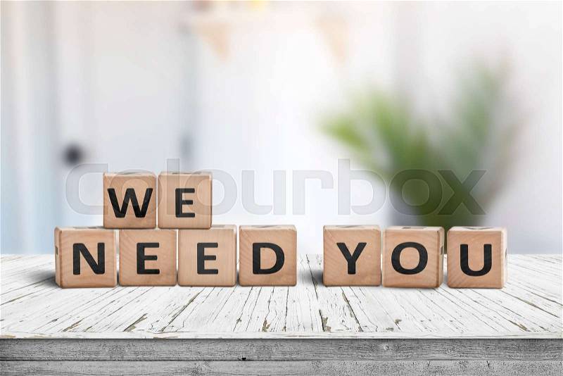 We need you sign on a white table in a bright room with a green plant, stock photo