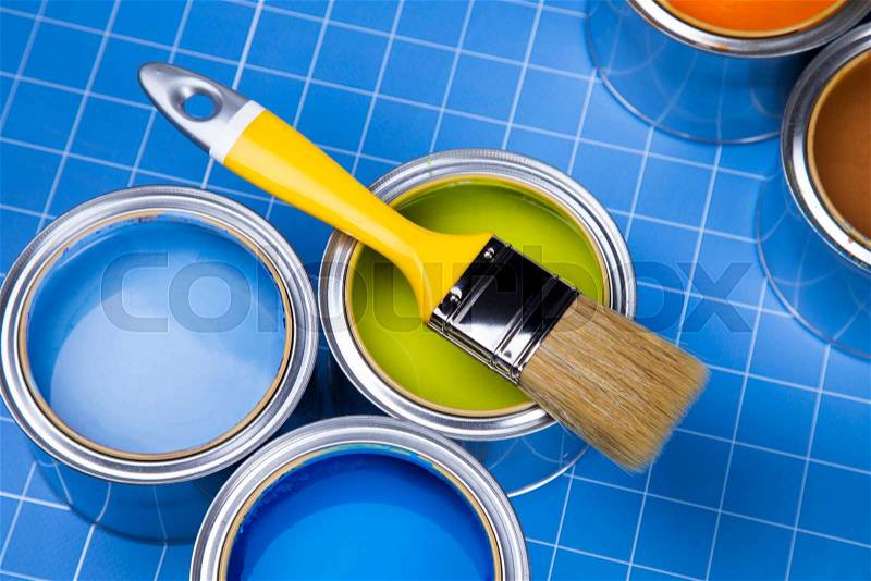 Metal tin cans with color paint and paintbrush, blue background, stock photo