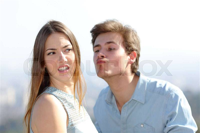 Angry woman rejecting a friend kiss in a sunny day, stock photo