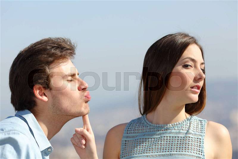 Woman rejecting a friend kiss in a sunny day, stock photo