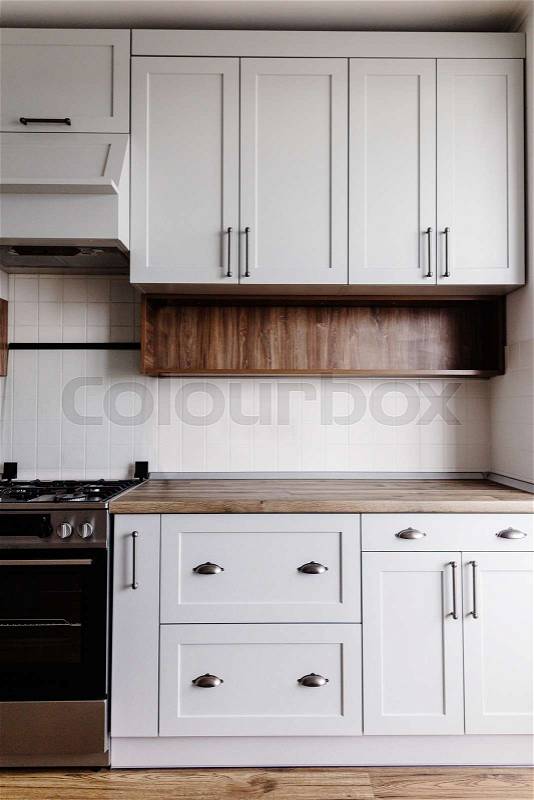 Luxury modern kitchen furniture in grey color and steel handle, oven, sink, wooden tabletop and floor. Gray cabinets in scandinavian style. Home renovation. Stylish ..., stock photo