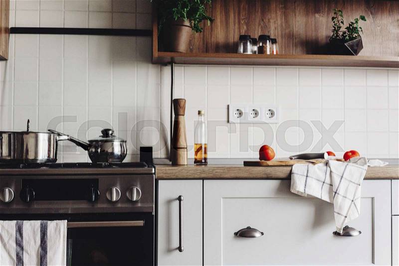 Cooking food on modern kitchen with steel oven, pots, knife on wooden cutting board with vegetables, pepper, spices,oil on wooden tabletop. Home food. Stylish ..., stock photo