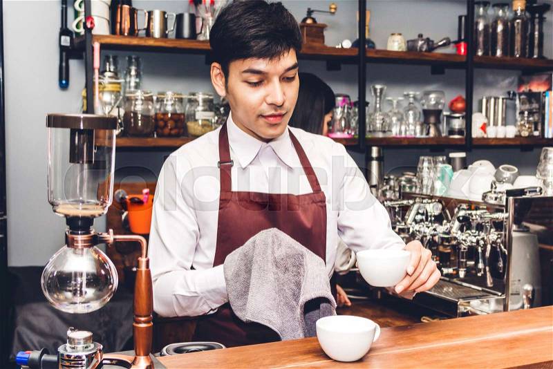 Portrait of couple small business owner smiling and working behind the counter bar in a cafe.Couple barista using coffee machine for making coffee at cafe, stock photo