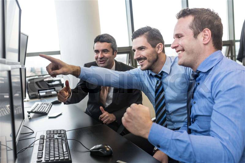 Successful business team. Excited stock traders looking at graphs, indexes and numbers on multiple computer screens. Colleagues in traders office. Business success, stock photo