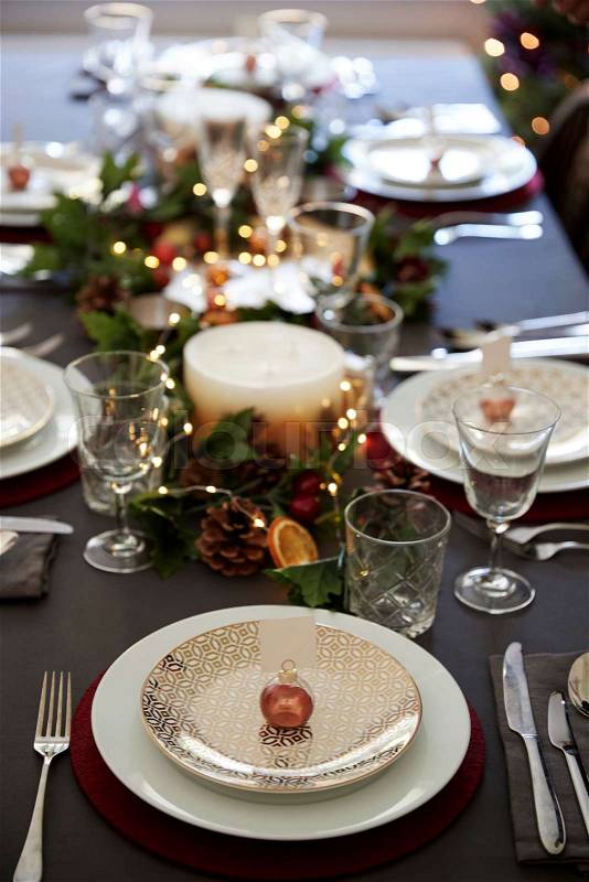 Christmas table setting with bauble name card holder arranged on a plate and green and red decorations, elevated view, stock photo