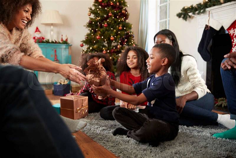 Son Giving Mother Gift As Multi Generation Family Celebrate Christmas At Home Together, stock photo