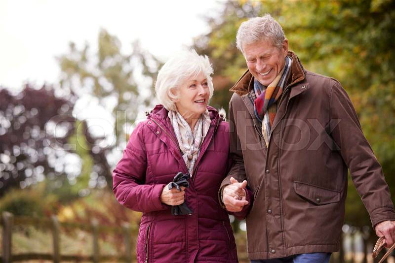 Active Senior Couple On Autumn Walk On Path Through Countryside, stock photo
