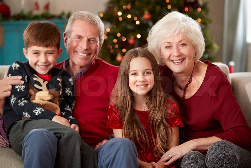Portrait Of Grandparents With Grandchildren Sitting On Sofa In Lounge At Home On Christmas Day, stock photo