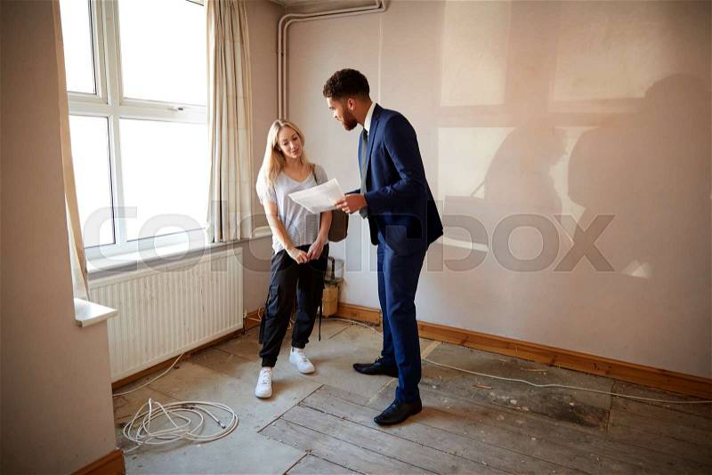 Female First Time Buyer Looking At House Survey With Realtor, stock photo