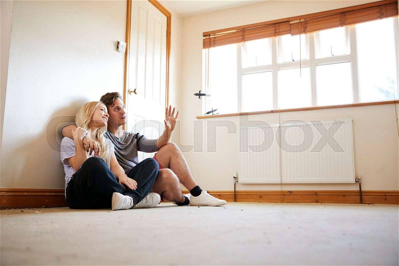 Couple Sitting On Floor In Empty Room Of New Home Planning Design, stock photo