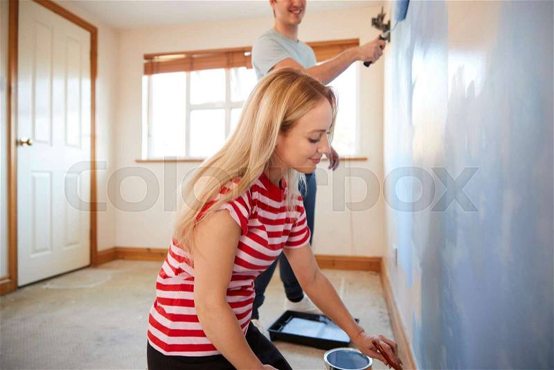 Couple Decorating Room In New Home Painting Wall Together, stock photo