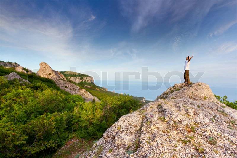 Hiker at the top of a rock with his hands up enjoy sunny day, stock photo